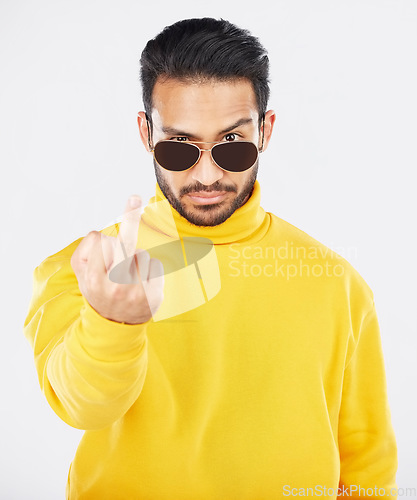 Image of Man, middle finger and sunglasses in studio portrait with anger, rude and frustrated by white background. Indian fashion model, guy and emoji for sign language, vote or opinion with hand for conflict