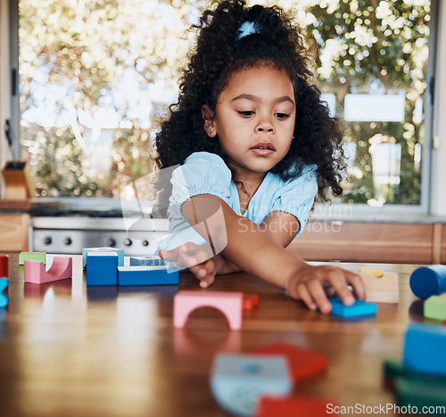 Image of Girl, child and learning with building blocks in home for education, development and playing puzzle games for growth. Kid, play and toys for teaching creative skills and relax with educational game