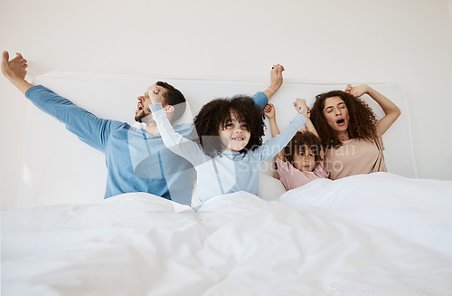 Image of Family, bed and yawn in morning wake up, relax or sleep together with arms up at home. Calm parents, children and bonding on holiday break, weekend or new day in peace, support or comfort in bedroom