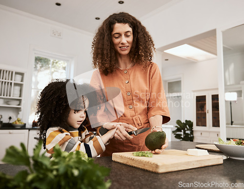 Image of Food, avocado and a mother cooking with her daughter in the kitchen of their home together for nutrition. Family, health or diet with a woman teaching her child about eating green vegetables