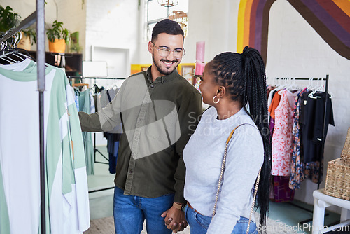 Image of Interracial couple, shopping and retail, clothes and fashion with happiness and commerce. Customer, people in boutique or shop holding hands with discount, sale and browsing in store at mall