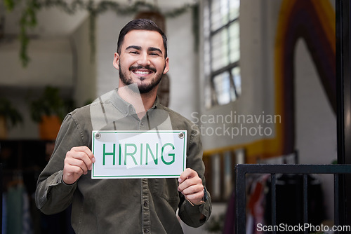 Image of Portrait, man and we are hiring opportunity sign with recruiting, happy and smile from business owner. Male person, store and entrepreneur with recruitment poster and job search signage with manager