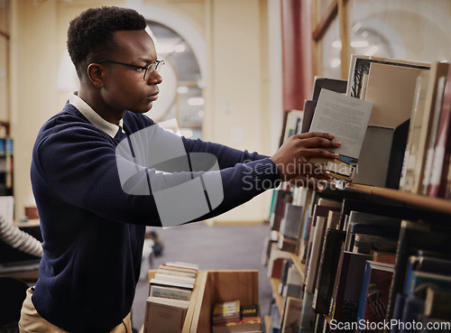 Image of University, research and man in a library reading and learning on campus for knowledge and education in college. Smart, clever and young person in an academy with books on a shelf for an exam