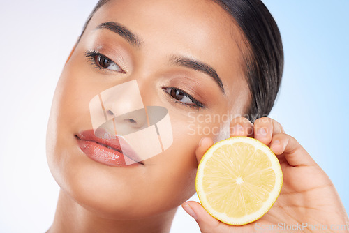 Image of Beauty, lemon and face of studio woman with citrus fruit for organic anti aging treatment, facial detox or aesthetic cosmetics. Vitamin C benefits, spa wellness and self care model on blue background