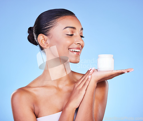 Image of Skincare, cream and product with woman and jar in studio for beauty, facial or moisturizer. Spa treatment, health and collagen with face of person on blue background for makeup, glow or sunscreen