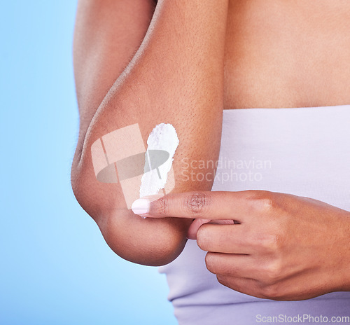 Image of Elbow, hand and cream, beauty and person with cosmetic product, moisturizer isolated on blue background. Treatment for dry skin, dermatology and apply sunscreen with skincare and lotion in studio