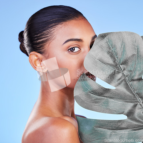 Image of Leaf, skincare and portrait of woman in studio for eco friendly, wellness or cosmetics on blue background. Monstera, face and Indian female with natural dermatology, beauty or organic body care