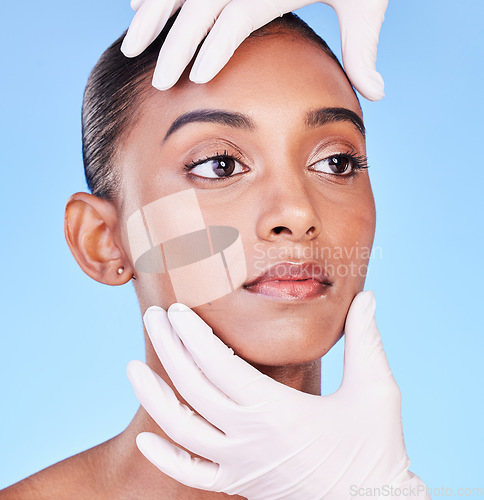 Image of Skincare, doctor and face of Indian woman for plastic surgery, cosmetics and facial treatment in studio. Dermatology, consulting and hands person for anti aging, botox and beauty on blue background