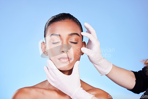 Image of Beauty, doctor and face of Indian woman for plastic surgery, cosmetics and facial treatment in studio. Dermatology, consulting and hands person for anti aging, botox and skincare on blue background