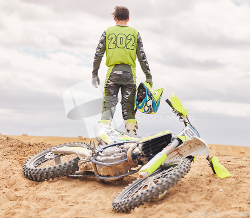 Image of Bike. sand and the back of a sports man outdoor on a dirt track after an accident or fall during a race. Motorcycle, freedom and challenge with a male athlete against a gray sky in the desert