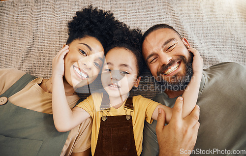 Image of Portrait, family and a boy with his parents on the floor of the living room in their home together from above. Face, smile or love with an interracial mother, father and son lying down closeup