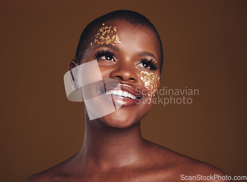 Image of Gold flakes, makeup and woman beauty with a smile from luxury treatment and facial spa. Glitter art, creative dermatology and African female person from skincare and golden cosmetics in studio