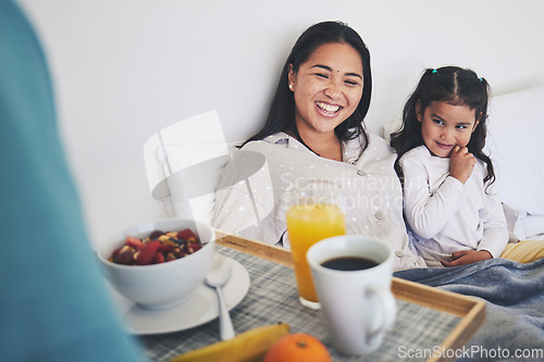 Image of Mother and daughter with breakfast in bed while relaxing for mothers day surprise at home. Happy, smile and young mom resting with girl child with a healthy meal for brunch on weekend at their house.