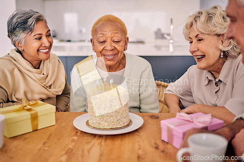 Image of Senior women, birthday cake candle and party at a home with a present and gift with excited friends. Surprise, event dessert and retirement of elderly group at dining room table together with a smile