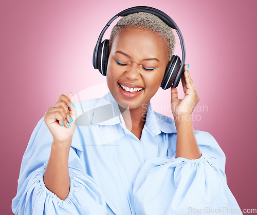 Image of Headphones, dance and happy black woman in studio with music, radio or streaming subscription on pink background. Podcast, earphones or African lady model dancing to album track or feel good playlist