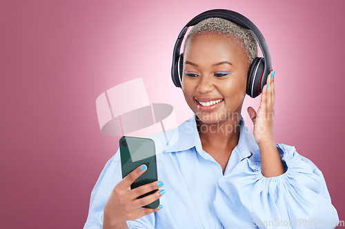 Image of Music, headphones and black woman with phone in studio for streaming, radio or listen on pink background. Smartphone, app and African lady model with online audio, podcast and earphones for album