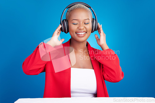 Image of Music, headphones and black woman dance in studio celebration with news, feedback or promo on blue background. Freedom, happy and African model dancing to earphones radio, podcast or audio streaming