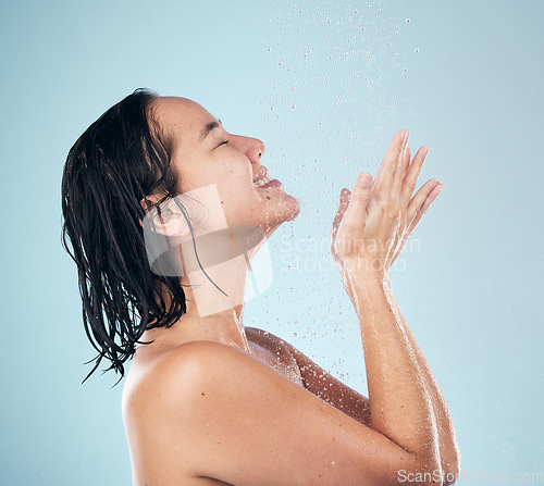 Image of Skincare, shower and woman smile cleaning in studio isolated on a blue background. Water splash, hygiene and model happy, washing and bathing in wellness, healthy skin beauty of body in bathroom.