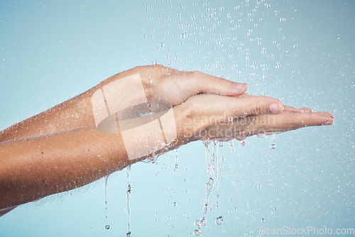 Image of Cleaning, hands and water splash on woman in studio, blue background and healthcare mockup and washing for skincare. Model, closeup or hygiene with clean, soap or bubbles for protection from bacteria