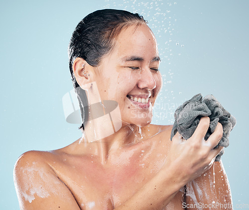 Image of Woman, shower and clean with water, soap and sponge for healthy dermatology, skincare and blue background in studio. Person, smile and washing skin, body and self care with cosmetics in bathroom