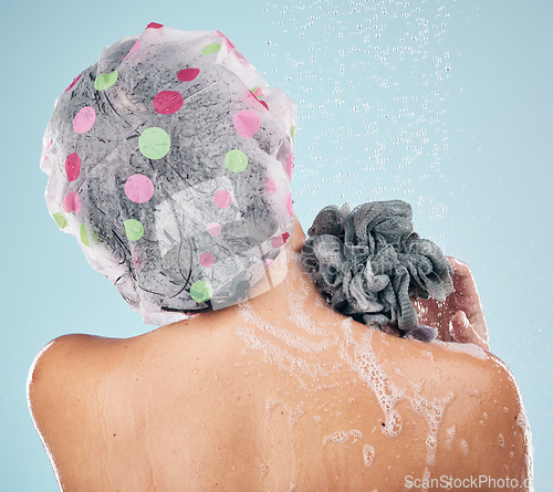 Image of Person, shower and back in water drops for hygiene, grooming or washing against a blue studio background. Rear view of model in soapy body wash, cleaning or skincare routine under rain in bathroom