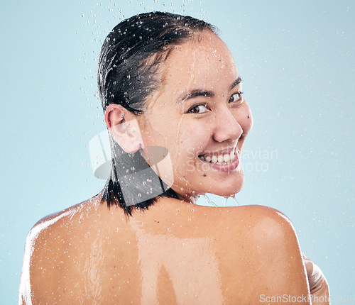 Image of Skincare, shower back and face of woman cleaning in studio isolated on a blue background. Water splash, hygiene and portrait of happy Asian model washing in bath for wellness, health and body beauty