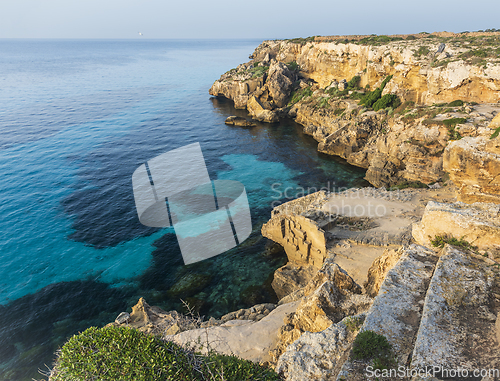 Image of A landscape with a rocky coast and blue water in the evening.