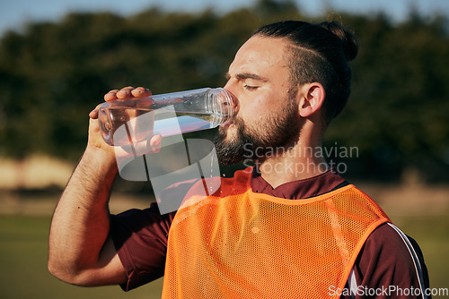 Image of Sports, drinking water and man in field to rest after training, workout and exercise outdoors. Fitness, health and male athlete with liquid bottle for wellness, nutrition and hydration for practice