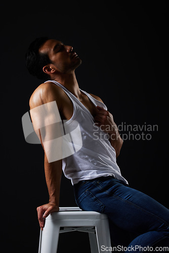 Image of Sexy, muscle and man on chair on black background with fitness inspiration, beauty aesthetic and sensual fashion. Erotic art, sexual body and male model sitting in studio, thinking in dark lighting.