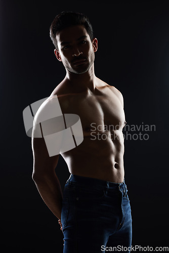 Image of Bodybuilder man, topless and muscle in studio for wellness, healthy body and black background. Young guy, fitness and silhouette in jeans, portrait and strong for fashion, shadow or shirtless for art