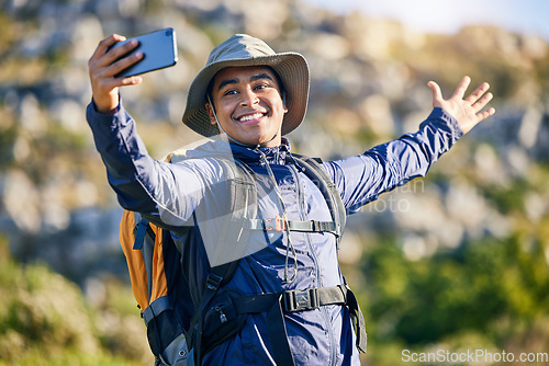 Image of Selfie, smile and a man hiking in the mountains for travel, adventure or exploration in summer. Nature, freedom and photography with a happy young hiker taking a profile picture outdoor in the sun