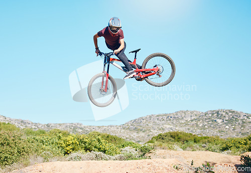 Image of Freedom, air and man cycling in nature training for a sports competition on trail or path on mountain. Action, stunt or cyclist athlete riding bicycle to jump for cardio exercise, fitness or workout