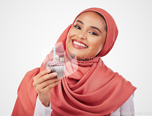 Image of Portrait, candle in a cupcake and an islamic woman in studio on white background for dessert. Face, smile and food with a happy young muslim person eating a cake, candy or sugar snack in celebration