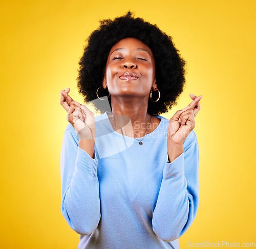 Image of Woman, fingers crossed and smile in studio for hope, trust and optimism of competition, prize or lottery. Happy african model wish for luck, bonus promotion and winning giveaway on yellow background