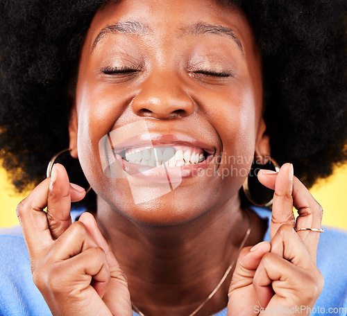 Image of Black woman, face and fingers crossed in studio for hope, trust and optimism of competition, prize and lottery. Happy model emoji for luck, bonus promotion and winning giveaway on yellow background