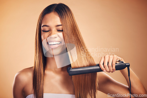 Image of Hair straightener, happy and woman in studio for beauty, cosmetics or appliance. Model person laugh on brown background for funny heat treatment, healthy results and hairdresser or salon flat iron