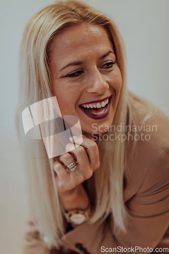 Image of A confident and successful businesswoman, with a wide smile, strikes a pose in front of a beige background, exuding professionalism and elegance