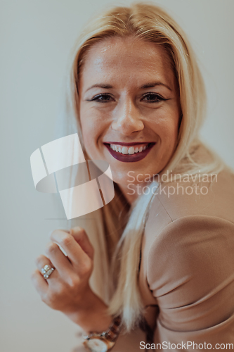 Image of A confident and successful businesswoman, with a wide smile, strikes a pose in front of a beige background, exuding professionalism and elegance