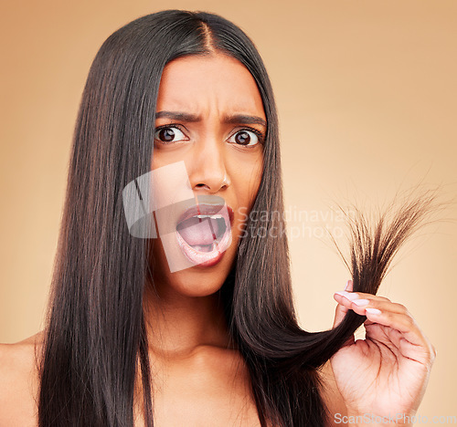 Image of Hair care, shock and portrait of woman in a studio with split ends for salon keratin treatment. Beauty, cosmetic and surprised Indian female model with hairstyle isolated by a brown background.