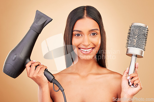 Image of Portrait, brush and hairdryer for haircare on a studio background for styling, grooming or a salon. Happy, ready and an Indian person or model with gear for drying a hairstyle or for a treatment