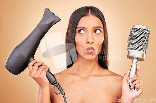 Image of Happy, thinking and a woman with a blowdryer on a studio background for haircare, styling or salon. Goofy, keratin and an Indian model or person with electric product for a hairstyle or treatment