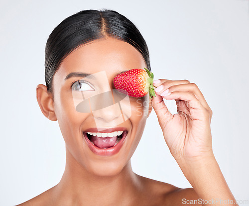 Image of Health, smile and woman with a strawberry in studio for healthy diet snack for nutrition. Wellness, beauty and young Indian female model with fruit for natural skin detox routine by white background.