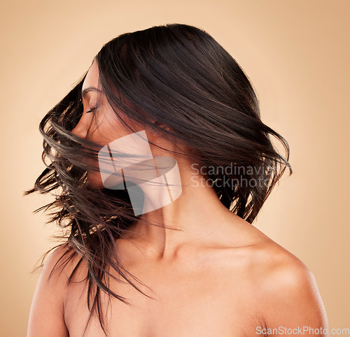 Image of Hair, beauty and woman shake head in studio isolated on a brown background. Hairstyle care, natural cosmetics and model in salon treatment for texture growth, health or wellness aesthetic with wind