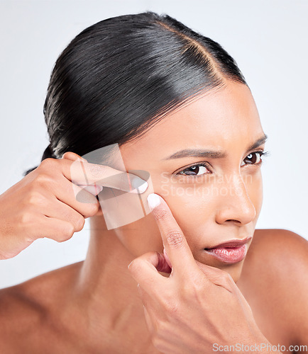 Image of Woman, face and squeeze acne in studio of breakout, dermatology or worry of scar on white background. Indian model check facial beauty to pop pimple, scratch blackhead or stress of sensitive skincare