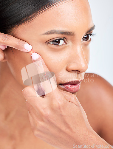 Image of Face, woman and squeeze acne in studio of glowing spot, breakout or check dermatology on white background. Indian model, facial beauty and pop pimple, scratch blackhead and scar of sensitive skincare