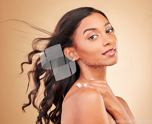 Image of Curly hair, face and woman in wind at studio isolated on a brown background. Hairstyle breeze, natural cosmetics and portrait of Indian model in salon treatment for beauty, hairdresser and balayage