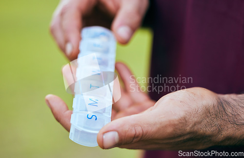 Image of Pill box, weekly medicine and hand closeup of a sport athlete on a soccer field with tablet and drugs for health. Supplements, plastic container and outdoor with a man holding wellness and medication