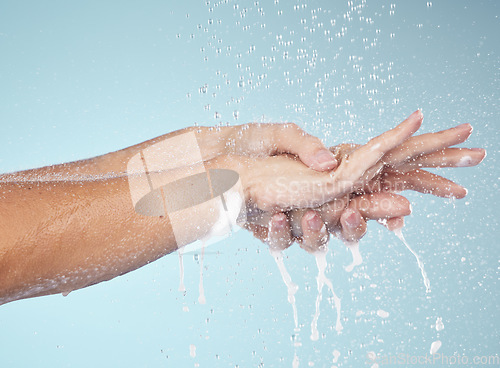 Image of Woman, cleaning and hands with water splash in studio, blue background and healthcare mockup or washing in skincare. Model, closeup or hygiene with clean, soap or bubbles for protection from bacteria