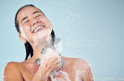 Image of Skincare, shower and woman smile with loofah in studio isolated on a blue background. Water splash, hygiene and model happy, washing and cleaning to bath in wellness, healthy body and mockup space