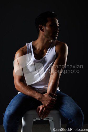 Image of Body, muscle and sexy man on chair in studio with fitness inspiration, aesthetic and sensual fashion. Art, wellness and performance, muscular male model on black background thinking in dark lighting.